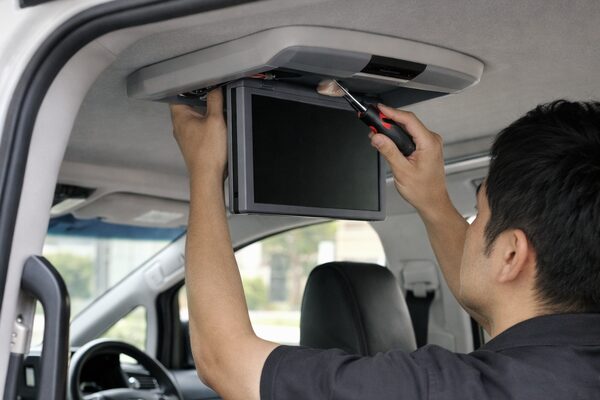 アルファードのフリップダウンモニターを専門業者が施工している様子