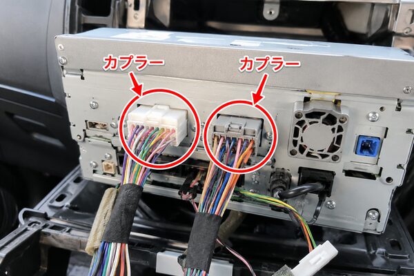 ナビ裏の配線に接続された白色とグレーのカプラーを赤丸と矢印で示した画像