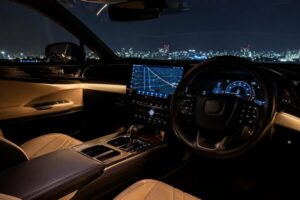 レクサスや高級SUVをイメージした右ハンドル車の高級インテリア。ブラック×ベージュの内装に暖色アンビエントライトが自然に溶け込み、夜景を背景に静かな高級感を演出している。